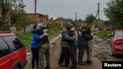 Los vecinos se abrazan después de regresar de la evacuación a la aldea liberada de Kamianka en la región de Kharkiv, Ucrania, el 2 de octubre de 2022.