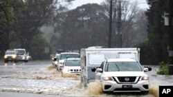 Cars slosh through a flooded road in Heathcote in Australia's Victoria State, Oct. 13, 2022.