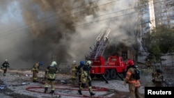 FILE - Firefighters help a woman evacuate from a residential building destroyed by a Russian drone strike, in Kyiv, Ukraine, Oct. 17, 2022. Local authorities said the weapon used was an Iranian-made Shahed-136.