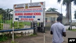 FILE - A man walks past the entrance of a bilingual school in Buea, the capital of the Southwest Region of Cameroon, Sept. 24, 2019