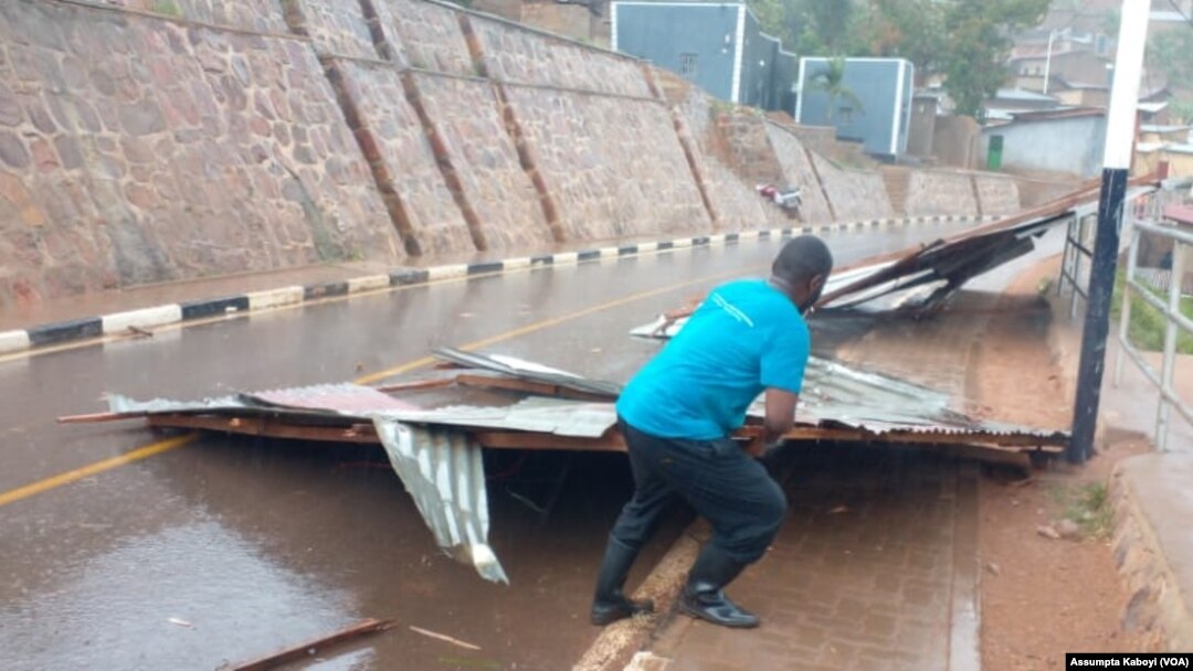 Umuturage ukura mu muhanda amabati y'inzu yasenywe n'imvura mu mujyi wa Kigali taliki 28-20-2022