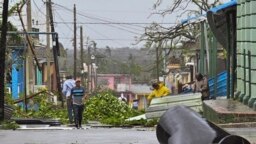 Orang-orang membersihkan jalan di Consolacion del Sur, Kuba, setelah dihantam badai Ian, 27 September 2022. (ADALBERTO ROQUE / AFP)
