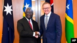 Perdana Menteri Australia Anthony Albanese, kanan, dan Perdana Menteri Kepulauan Solomon Manasseh Sogavare berjabat tangan menjelang pertemuan bilateral di Gedung Parlemen di Canberra, Australia, 6 Oktober 2022. (Foto: via AP)