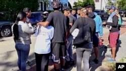 FILE - A group of immigrants gather outside St. Andrews Episcopal Church, Sept. 15, 2022, in Edgartown, Mass., on Martha's Vineyard. 