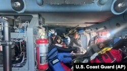 In this image provided by the U.S. Coast Guard, a Coast Guard Air Station New Orleans MH-60 Jayhawk aircrew treats rescued boaters for injuries Oct. 9, 2022. The three rescued men, whose fishing boat sank in the Gulf of Mexico off the coast of the U.S. state of Louisiana, were pulled out of the water after surviving more than a day despite being attacked by sharks.