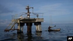 FILE - A fisherman navigates past a disused oil well in Venezuela on October 12, 2022.  A 49-page indictment has charged seven people with conspiring to smuggle oil from PDVSA, buy sensitive US military technology and launder tens of millions