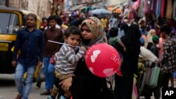 Seorang perempuan Muslim yang mengenakan hijab tampak membawa anaknya berjalan di area pasar di Bengaluru, India, pada 13 Oktober 2022. (Foto: AP/Aijaz Rahi)