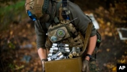 A Ukrainian territorial defense deminer takes Russian ammunition left behind as his team clears mines near Grakove village, Oct. 13, 2022.
