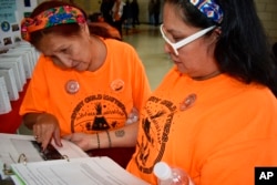 Ruby Left Hand Bull Sanchez, left, points to a photo of the Native American boarding school she was forced to attend, as her daughter Candice Left Hand Bull Vigil looks on at Sinte Gleska University on the Rosebud Sioux Reservation in Mission, S.D., Oct. 15, 2022.