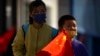 A boy wearing a face mask carries a Chinese flag as he walks along a pedestrian shopping street in Beijing, Oct. 6, 2022.