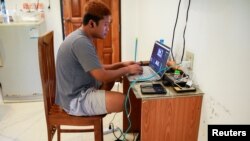 FILE - Journalist Min Het Mone works in his room, at the Thai-Myanmar border, Jan. 26, 2022.
