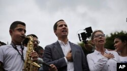 ARCHIVO - El líder opositor Juan Guaidó y la congresista Olivia Lozano se unen al canto del himno nacional durante un mitin en Caracas, Venezuela, el sábado 11 de mayo de 2019.