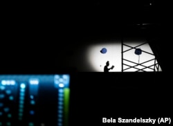 Shadow of a technician is seen on the stage of the Trafo House of Contemporary Arts while others set up the lightings, Sept. 19, 2022. (AP Photo/Bela Szandelszky)