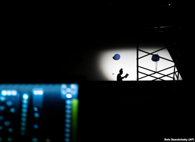 Shadow of a technician is seen on the stage of the Trafo House of Contemporary Arts while others set up the lightings, Sept. 19, 2022. (AP Photo/Bela Szandelszky)