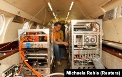 Seorang anggota staf teknis menyiapkan mesin pengukur di dalam pesawat penelitian Falcon 20E sebagai ilustrasi. (Foto: Reuters/Michaela Rehle)