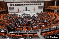 FILE - Turkey's main opposition Republican People's Party (CHP) lawmakers hold placards as they protest a contentious media bill, at the Turkish parliament in Ankara, Turkey, Oct. 4, 2022.