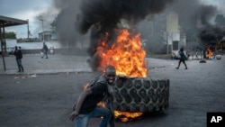 A protester adds a tire to a burning barricade during a protest against fuel price hikes and to demand that Haitian Prime Minister Ariel Henry step down, in Port-au-Prince, Haiti, Sept. 16, 2022.