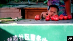 FILE - A Uyghur child plays with tomato at a street vender in Urumqi, western China's Xinjiang province, July 11, 2009. 