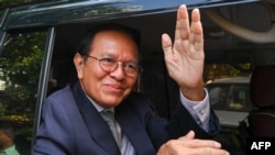 Kem Sokha, former leader of the now-dissolved Cambodia National Rescue Party (CNRP), greets the media at his home before going to Phnom Penh Municipal Court for his treason trial in Phnom Penh on October 19, 2022. (Photo by TANG CHHIN Sothy / AFP)