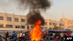 Una imagen obtenida por AFP fuera de Irán muestra a personas reunidas junto a una motocicleta en llamas en la capital, Teherán, el 8 de octubre de 2022.