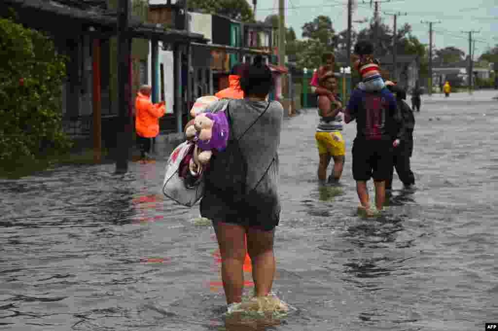 Varias personas caminan por una calle inundada en Batabanó, Cuba, el 27 de septiembre de 2022, durante el paso del huracán Ian. (Foto de YAMIL LAGE / AFP)