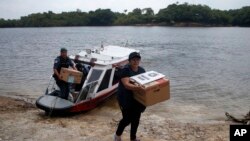 An electoral worker and a military police officer unload electronic voting machines to be taken to a polling station a day ahead of the country's general elections, at the Bela Vista do Jaraqui community in Manaus, Amazonas state, Brazil, Oct. 1, 2022. 