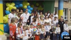 Niños de una escuela primaria reconstruida posan al iniciar clases del año escolar en Bucha, ciudad periférica de Kiev en Ucrania. [Imagen: Captura de pantalla de reportaje producido por VOA]