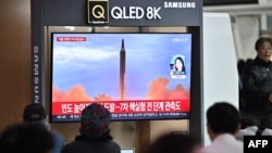 FILE - People sit in front of a television screen showing a news broadcast with file footage of a North Korean missile launch, at a railway station in Seoul, South Korea, Oct. 6, 2022.