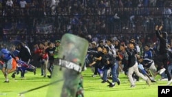 Soccer fans enter the pitch during a clash between supporters at Kanjuruhan Stadium in Malang, East Java, Indonesia, Oct. 1, 2022.