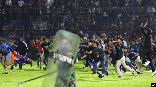 Soccer fans enter the pitch during a clash between supporters at Kanjuruhan Stadium in Malang, East Java, Indonesia, Oct. 1, 2022.