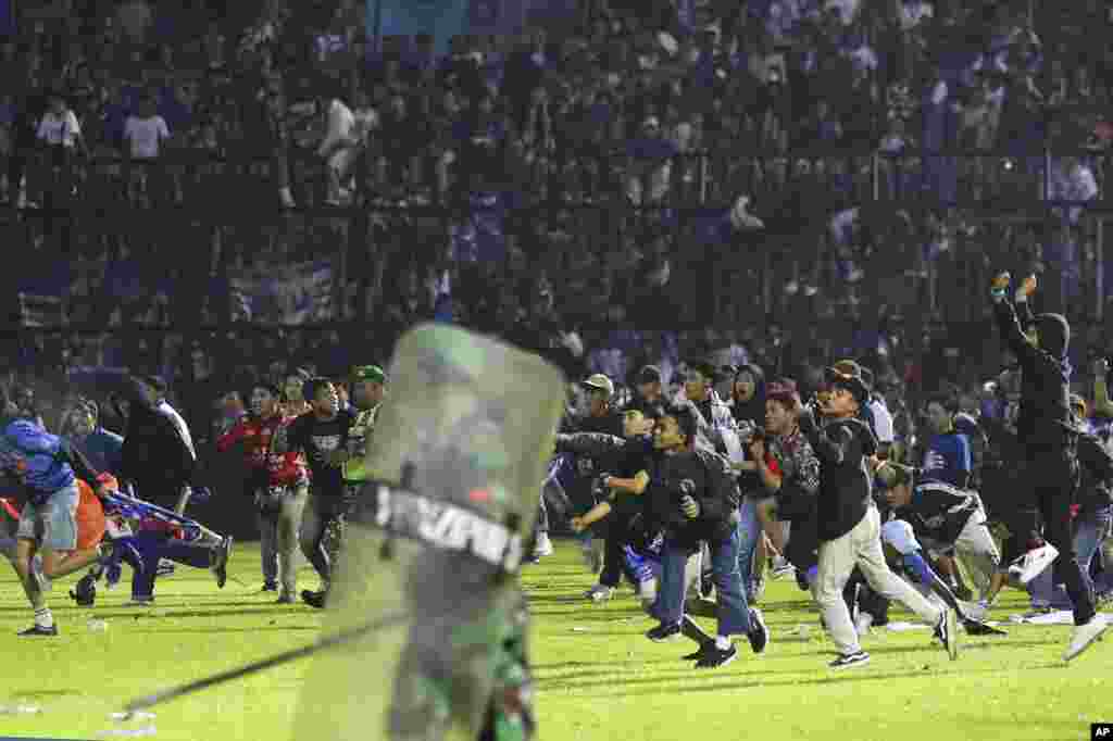 Para penggemar sepak bola memasuki lapangan saat bentrokan antara pendukung di Stadion Kanjuruhan di Malang, Jawa Timur, Indonesia, 1 Oktober 2022. (Foto: AP/ Yudha Prabowo)