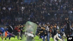 Soccer fans enter the pitch during a clash between supporters at Kanjuruhan Stadium in Malang, East Java, Indonesia, Oct. 1, 2022.