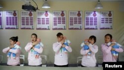 FILE - Students at Ayi University, a training program for domestic helpers, practice on baby dolls during a course teaching childcare in Beijing, China December 5, 2018. (REUTERS/Thomas Peter/File Photo)