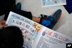 Children read as Ian Ellis James, an Emmy award-winning Sesame Street writer known by his stage name William Electric Black, leads a first grade class in a book reading on urban gun violence prevention at the Drexel Avenue School, Monday, Oct. 3, 2022, in Westbury, N.Y. (AP Photo/John Minchillo)