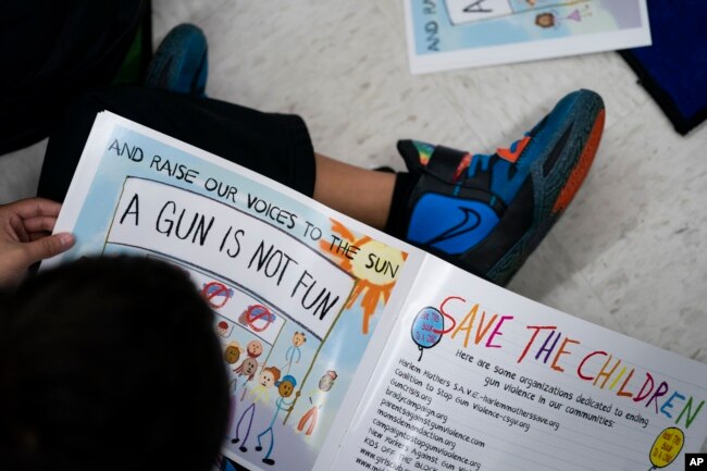 Children read as Ian Ellis James, an Emmy award-winning Sesame Street writer known by his stage name William Electric Black, leads a first grade class in a book reading on urban gun violence prevention at the Drexel Avenue School, Monday, Oct. 3, 2022, in Westbury, N.Y. (AP Photo/John Minchillo)