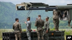 Filipino and American Marines talk beside a U.S. High Mobility Artillery Rocket System (HIMARS) during a Combined Arms Live Fire Exercise (CALFEX) as part of the annual combat drills between the Philippine Marine Corps and U.S. Marine Corps in Capas, Tarl