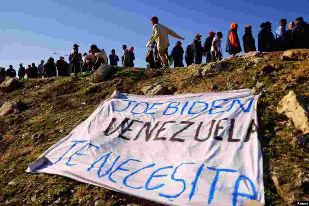 Migrantes venezolanos, algunos expulsados de EEUU a México bajo el Título 42 y otros que aún no han cruzado tras las nuevas políticas migratorias, hacen fila para recibir alimentos donados mientras una pancarta que dice &quot;Joe Biden Venezuela te necesita&quot; yace a orillas del Río Bravo, en Ciudad Juárez, México, el 26 de octubre de 2022. REUTERS/José Luis González&nbsp;&nbsp;