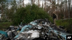 A Ukrainian serviceman walks over the remains of Russian aircraft SU-34 in an area at the recaptured town of Lyman, Ukraine, Oct. 5, 2022. 