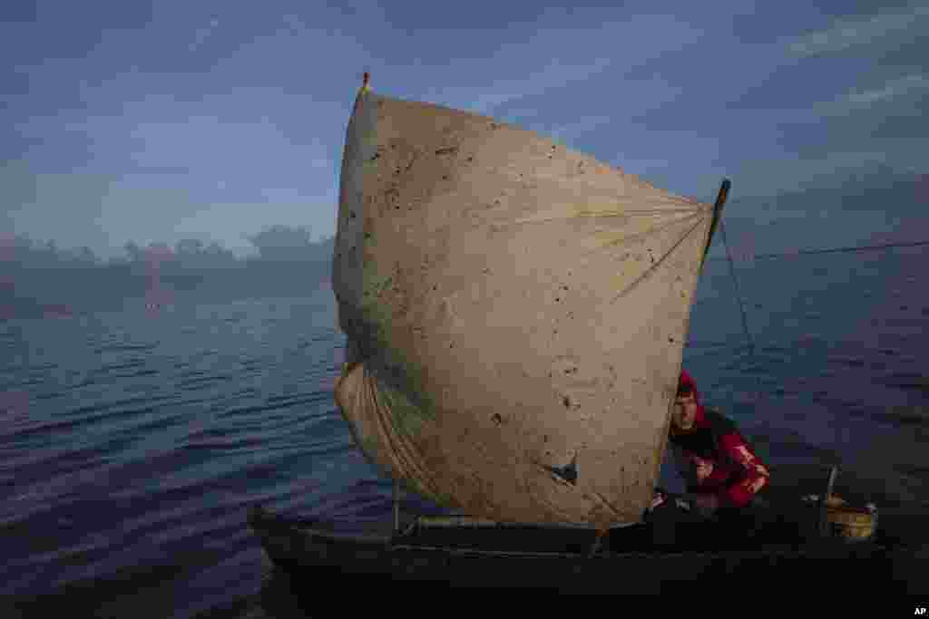 Yohandry Colina uses an oil-stained sheet for a sail on the boat he uses to put fish he catches in Lake Maracaibo in Cabimas, Venezuela, Oct. 12, 2022. 