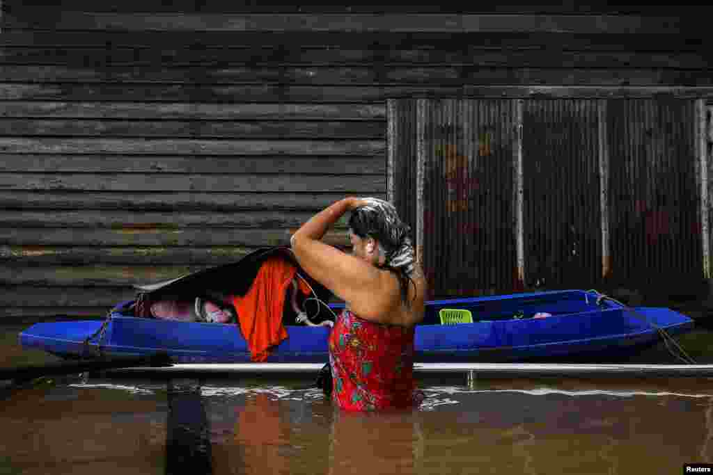 A woman washes her hair on a flooded road after heavy rainfall near Tha-it mosque in Nonthaburi province outskirt of Bangkok, Thailand.