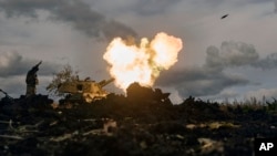 A Ukrainian serviceman reacts as a self-propelled artillery vehicle fires near Bakhmut, Donetsk region, Ukraine, Oct. 22, 2022. 
