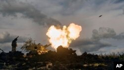 A Ukrainian serviceman reacts as a self-propelled artillery vehicle fires near Bakhmut, Donetsk region, Ukraine, Oct. 22, 2022. 