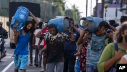 FILE - People carry fuel cylinders after they purchased it at a distribution heart, in Colombo, Sri Lanka, July 12, 2022. Most Asian international locations are prioritizing protecting the nation operating, irrespective of the power supply.