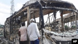 FILE - People inspect burned-out government transportation buses at the Berger station near Ikeja, Lagos, Nigeria, Oct. 22, 2020. Lagos streets were empty and shops were shuttered that day as most residents of Lagos obeyed the government's curfew, stopping the protests against police brutality that had lasted for two weeks.