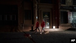 La gente camina con sus perros en una calle de Zaporizhzhia, Ucrania, el 19 de octubre de 2022.