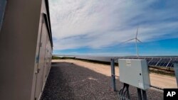 In this photo provided by Portland General Electric, windmills and solar panels are seen on May 24, 2022, at a renewable energy facility in Lexington, Ore.