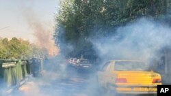In this Saturday, Oct. 1, 2022, photo taken by an individual not employed by the Associated Press and obtained by the AP outside Iran, tear gas is fired by security to disperse protestors in front of the Tehran University, Iran. 