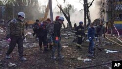 In this photo provided by the Ukrainian Emergency Service, rescuers work at the scene of a building damaged by shelling in Zaporizhzhia, Ukraine, Oct. 9, 2022. 