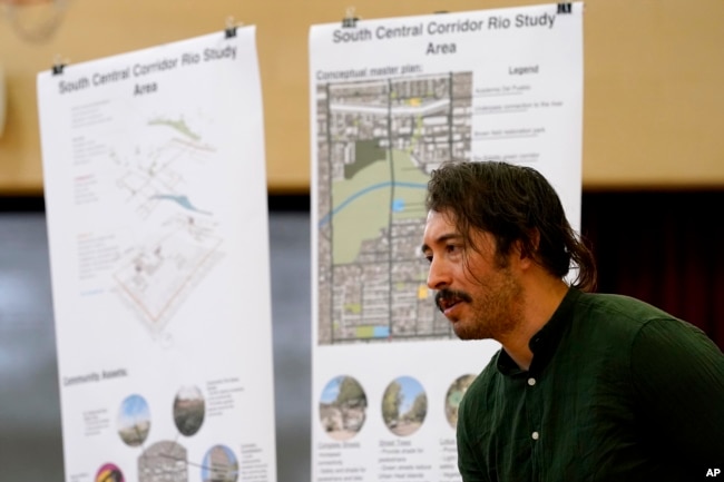 Environmental activist Reggie Carrillo speaks with community members, Friday, Sept 28, 2022, in Phoenix. Carrillo has benefited from one of several nonprofit initiatives to educate and engage residents about climate fueled heat that disproportionately affects low income neighborhoods of color. (AP Photo/Matt York)