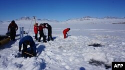 This handout picture taken on May 29, 2017, shows researchers drilling holes to collect sediment at the Lake Hazen in the Arctic to investigate how climate change might increase the risk of "viral spillover." (Photo by Graham Colby via AFP)